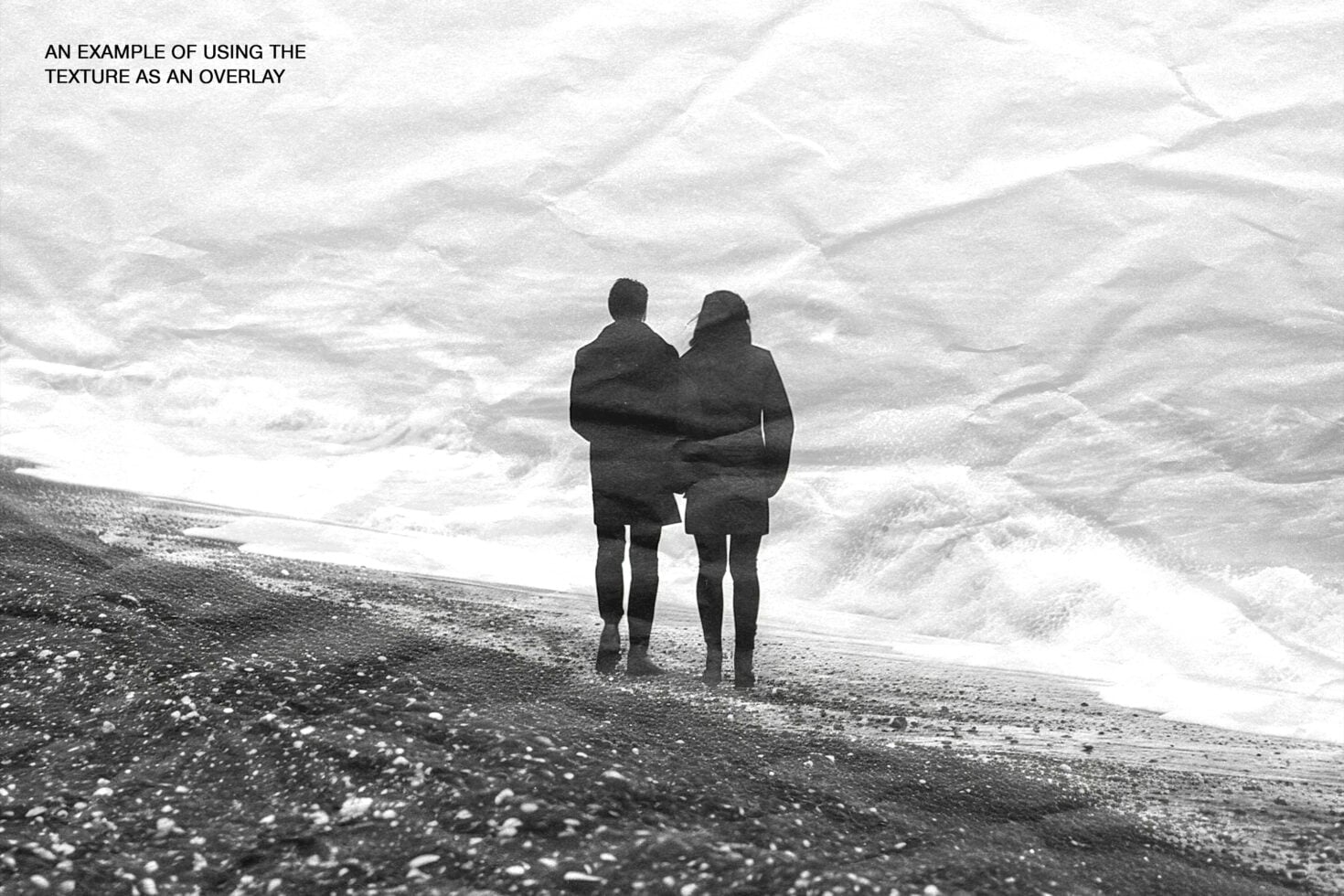 Two people in wetsuits standing in ocean waves, black over white crumpled paper overlay