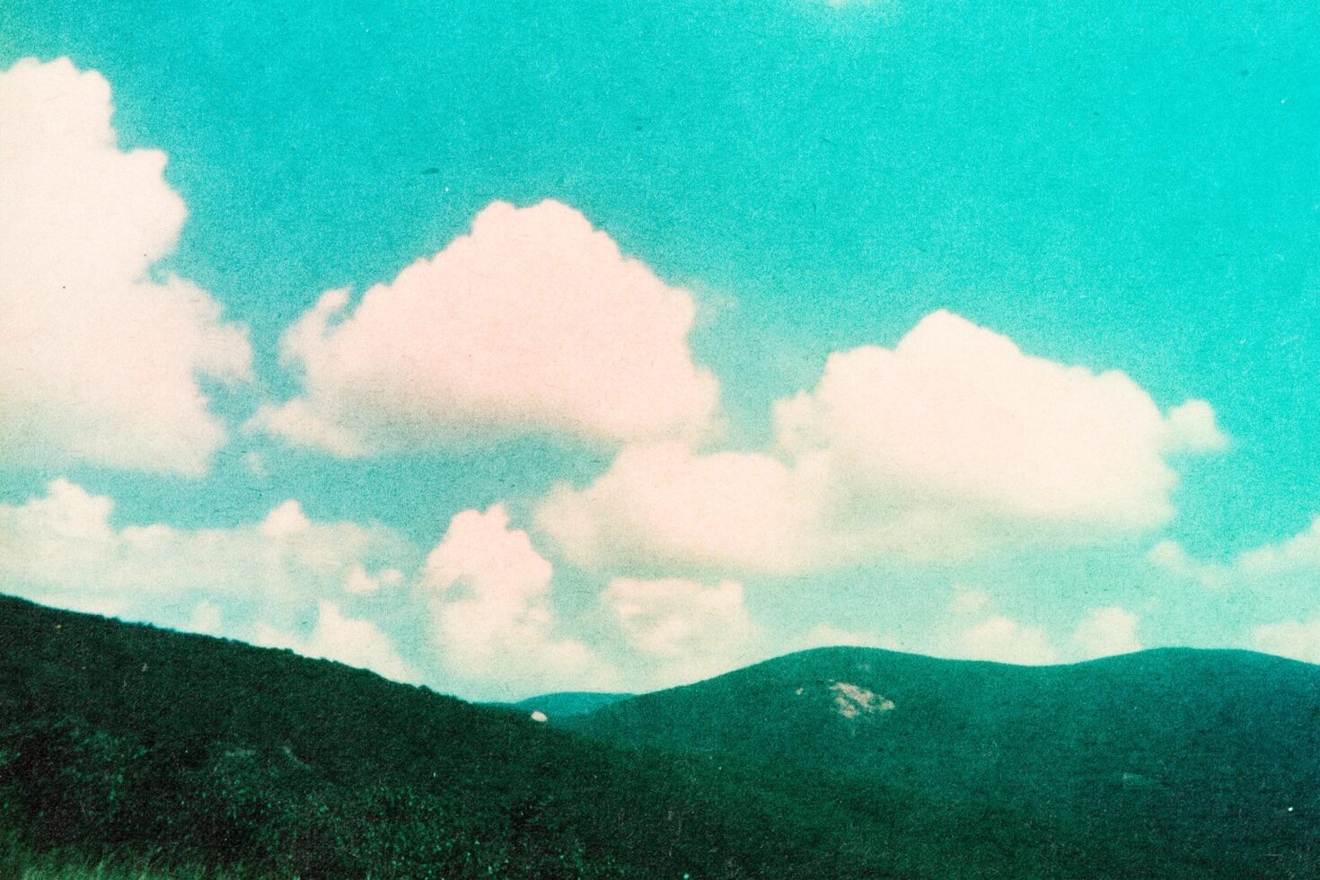 Retro landscape with hills and fluffy clouds under a teal sky. Ideal for graphic design projects or as a digital template background asset.