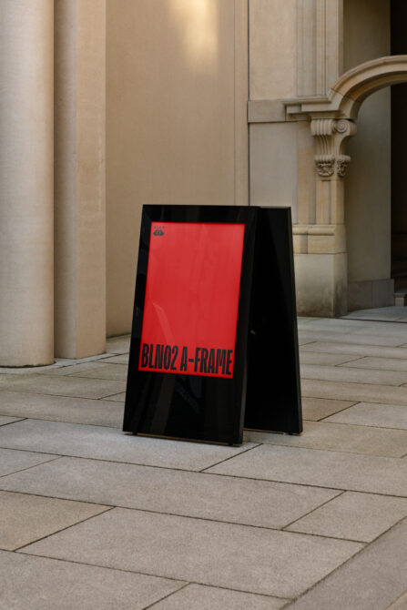 Black A-frame sidewalk sign with bright red panel in classical corridor setting