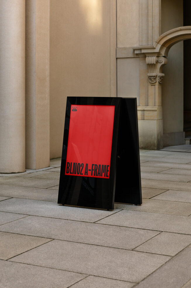 Black A-frame sidewalk sign with bright red panel in classical corridor setting