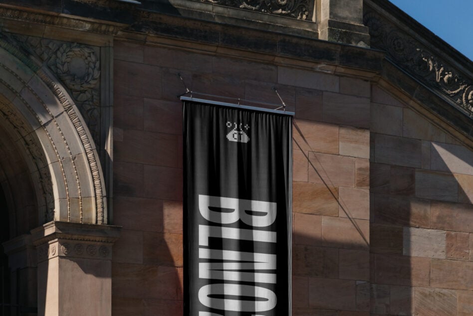 Black fabric banner with white striped text on historic stone building facade