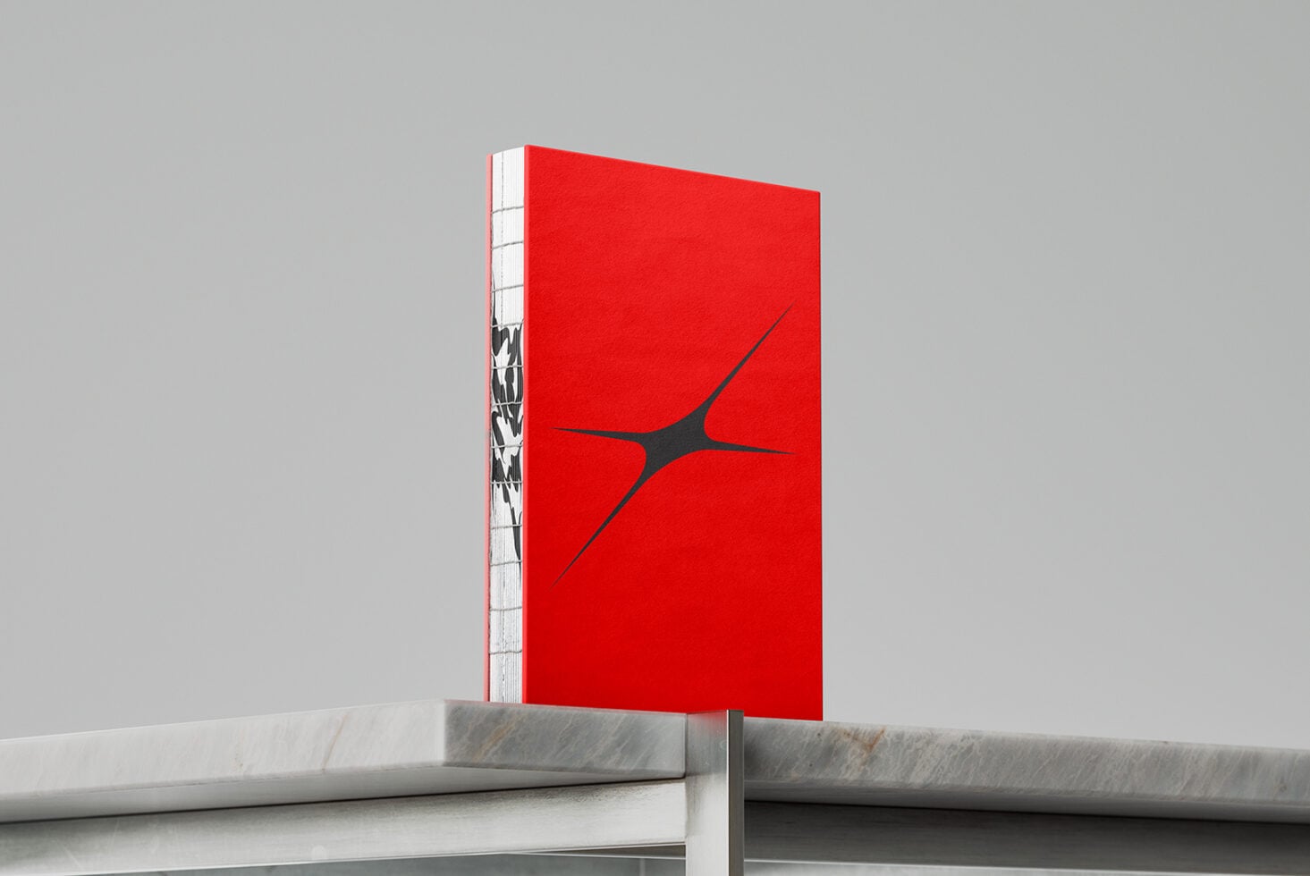 Red hardcover book with black geometric mark on marble shelf