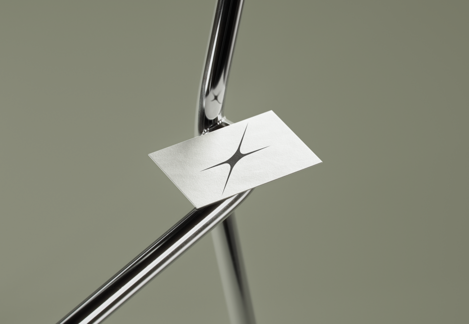 Business card mockup with four-point star logo on white paper held by chrome clamp