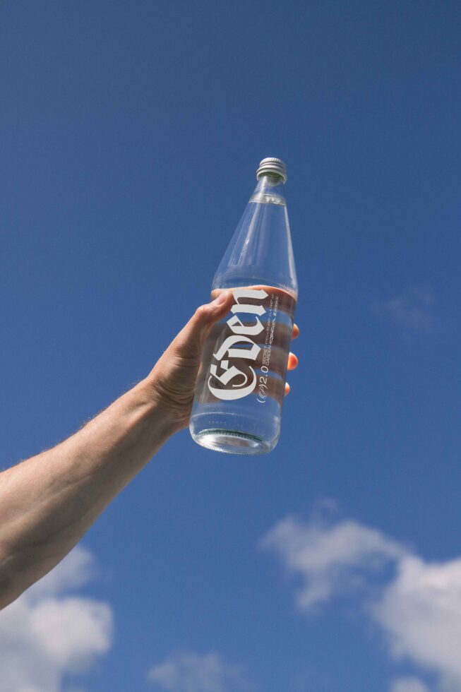 Hand holding bottle against blue sky design mockup potential digital asset font logo branding minimalist graphic designer resource creative template