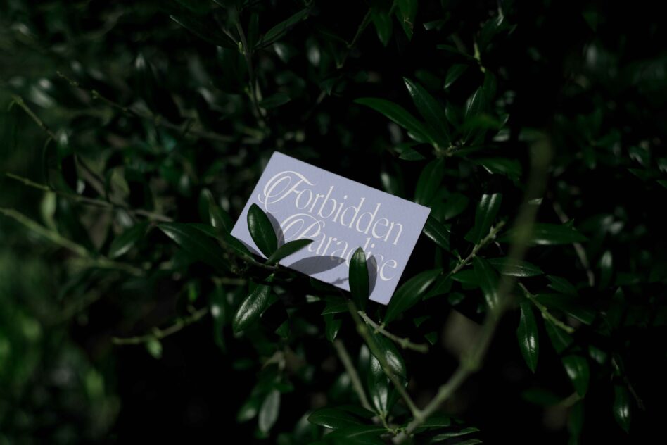 Light purple card with white stylized lettering in natural garden setting
