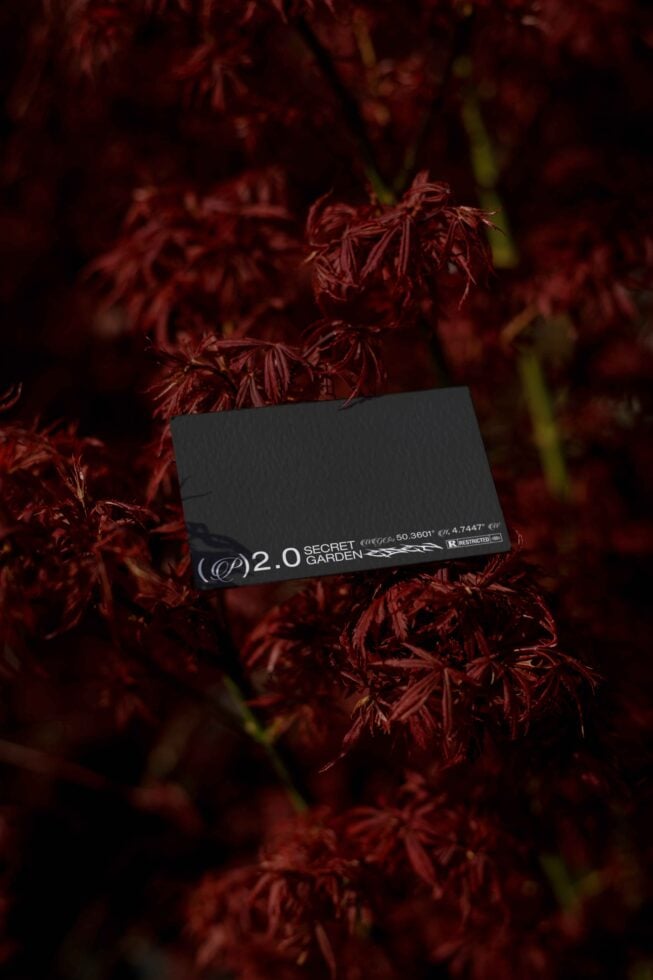 Dark business card with Secret Garden branding nestled in deep red maple leaves