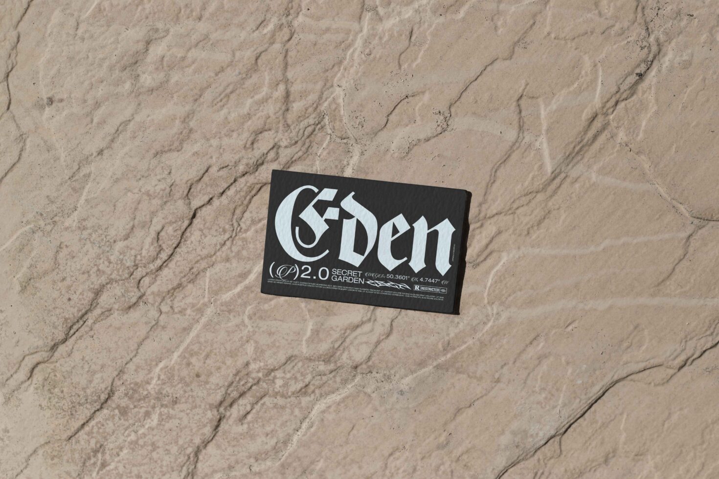 Black business card with 'Eden' typeface positioned on sandy textured ground
