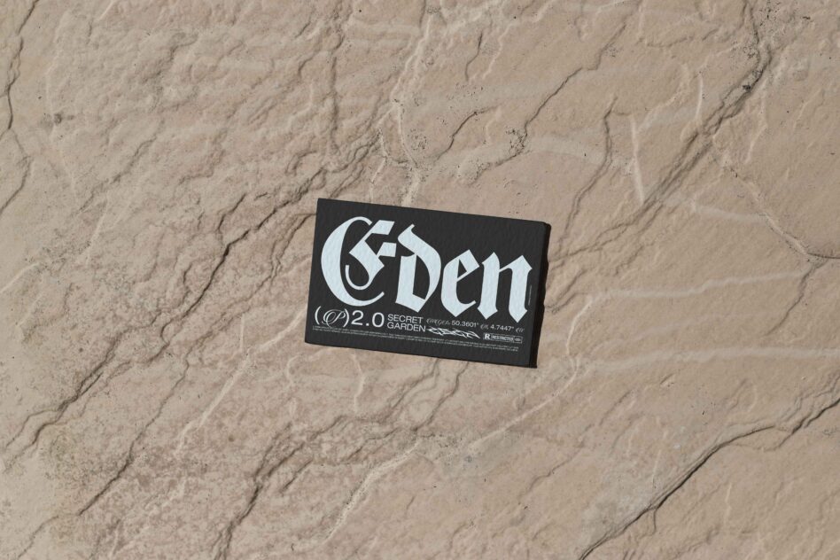 Black business card with 'Eden' typeface positioned on sandy textured ground