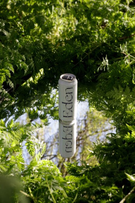 Tall white cylindrical can mockup with Eden text centered in bright green fern canopy