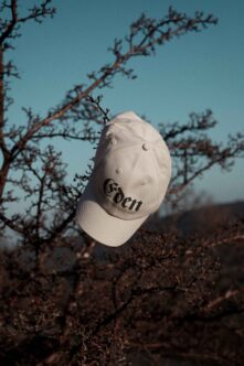 White baseball cap with Eden logo displayed floating against dry desert branches