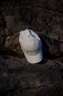 White Edlen cap with embroidered logo on weathered rocky surface