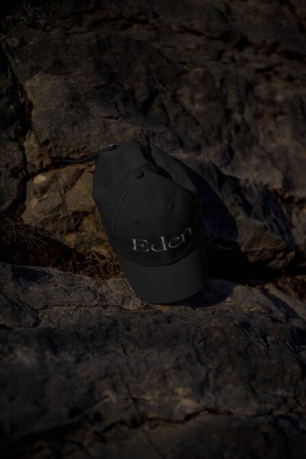 Black Edlen cap with embroidered logo resting on weathered stone