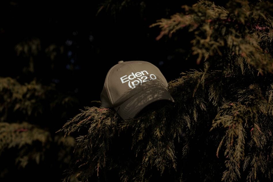 Green baseball cap with Eden 2.0 text placed on a tree branch in a natural setting perfect for designers seeking outdoor-themed mockup graphics templates