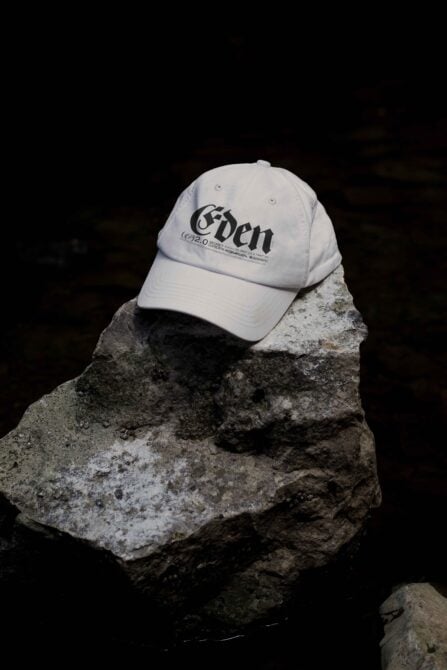 Light colored cap with Eden logo resting on weathered stone with dramatic shadows