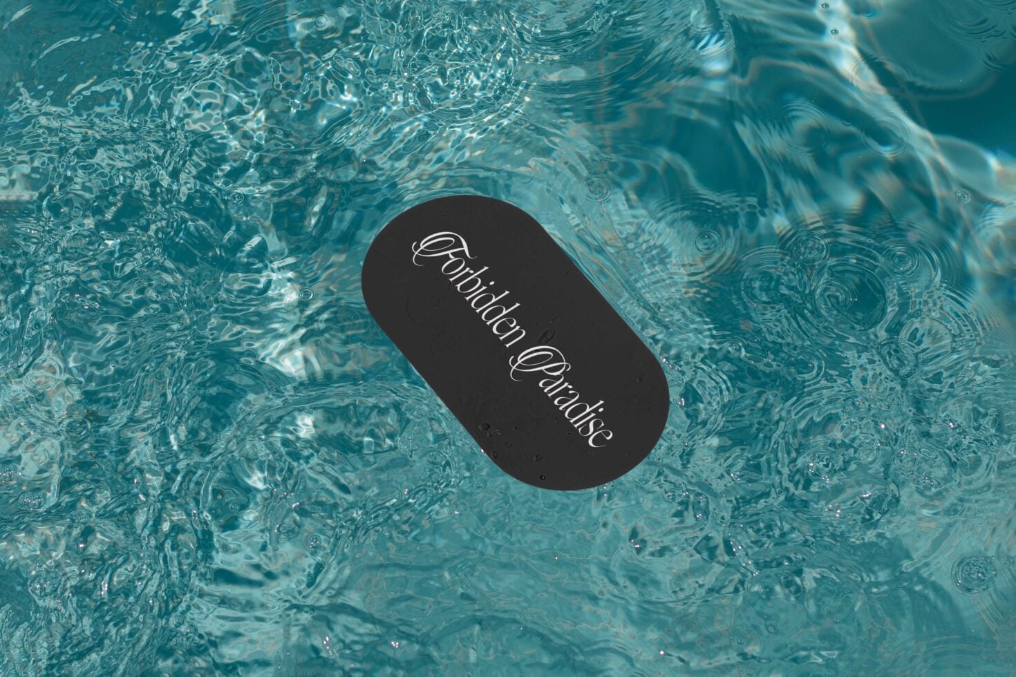 Black oval label floating in clear turquoise pool water with script typography