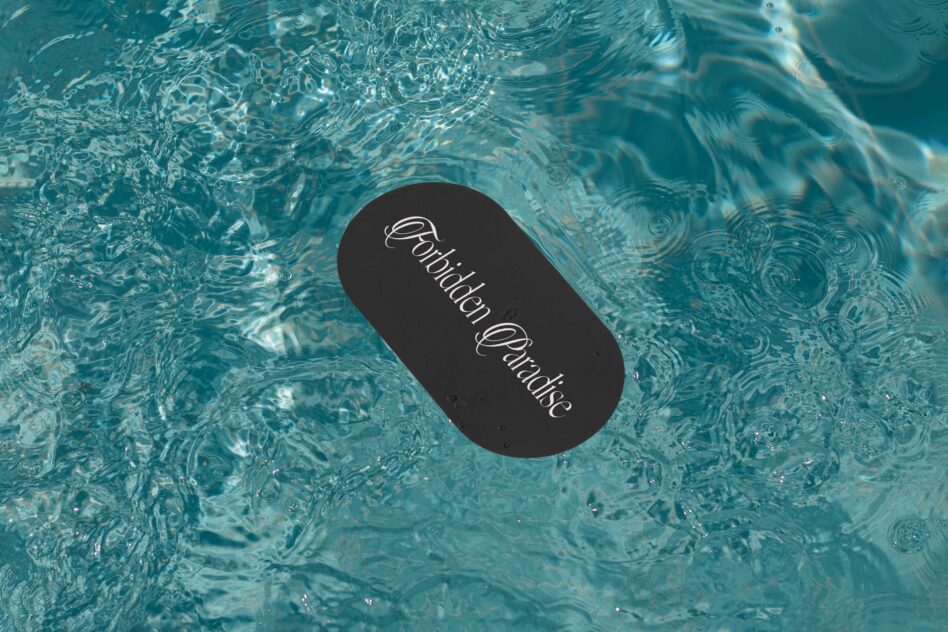 Black oval label floating in clear turquoise pool water with script typography