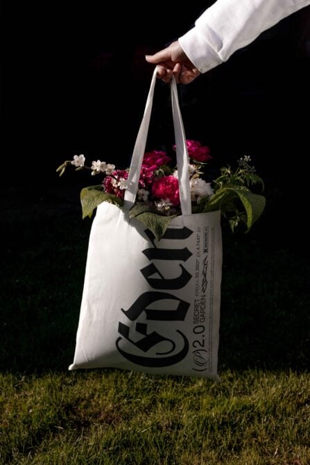 Tote bag mockup with bold typography design, filled with pink and white flowers, perfect for graphic designers seeking creative templates and inspiration.