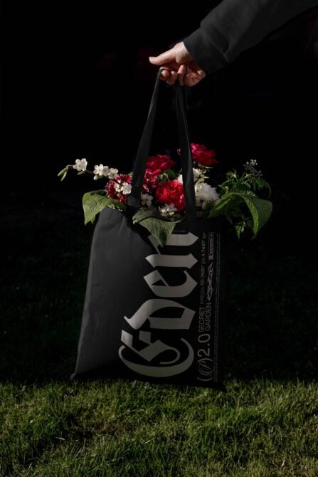 Designer tote bag mockup with gothic typography filled with vibrant flowers against a dark background perfect for showcasing branding templates.