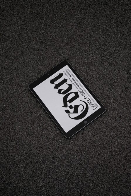 Tablet mockup on textured dark surface showing large black serif font design