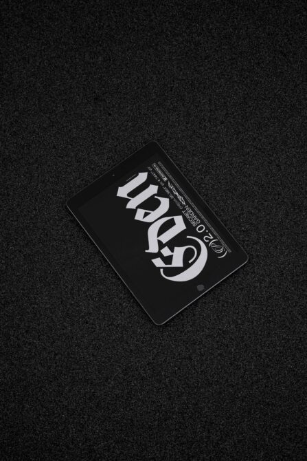Black tablet with white serif letters on dark background, angled overhead shot