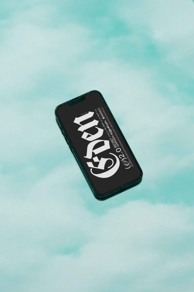 Phone mockup with gothic font design on screen floating against teal cloudy sky background digital asset for graphic designers templates mockups fonts.