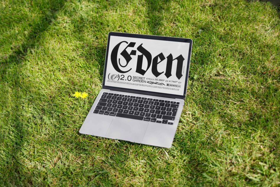 Silver laptop showing Eden design on green grass with yellow flower