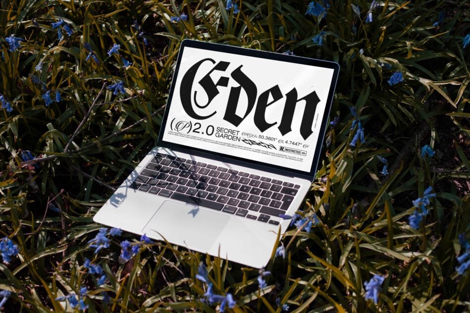 Laptop displaying bold Gothic typography design in a natural setting with blue flowers for designers. Ideal for fonts category in digital asset marketplace.