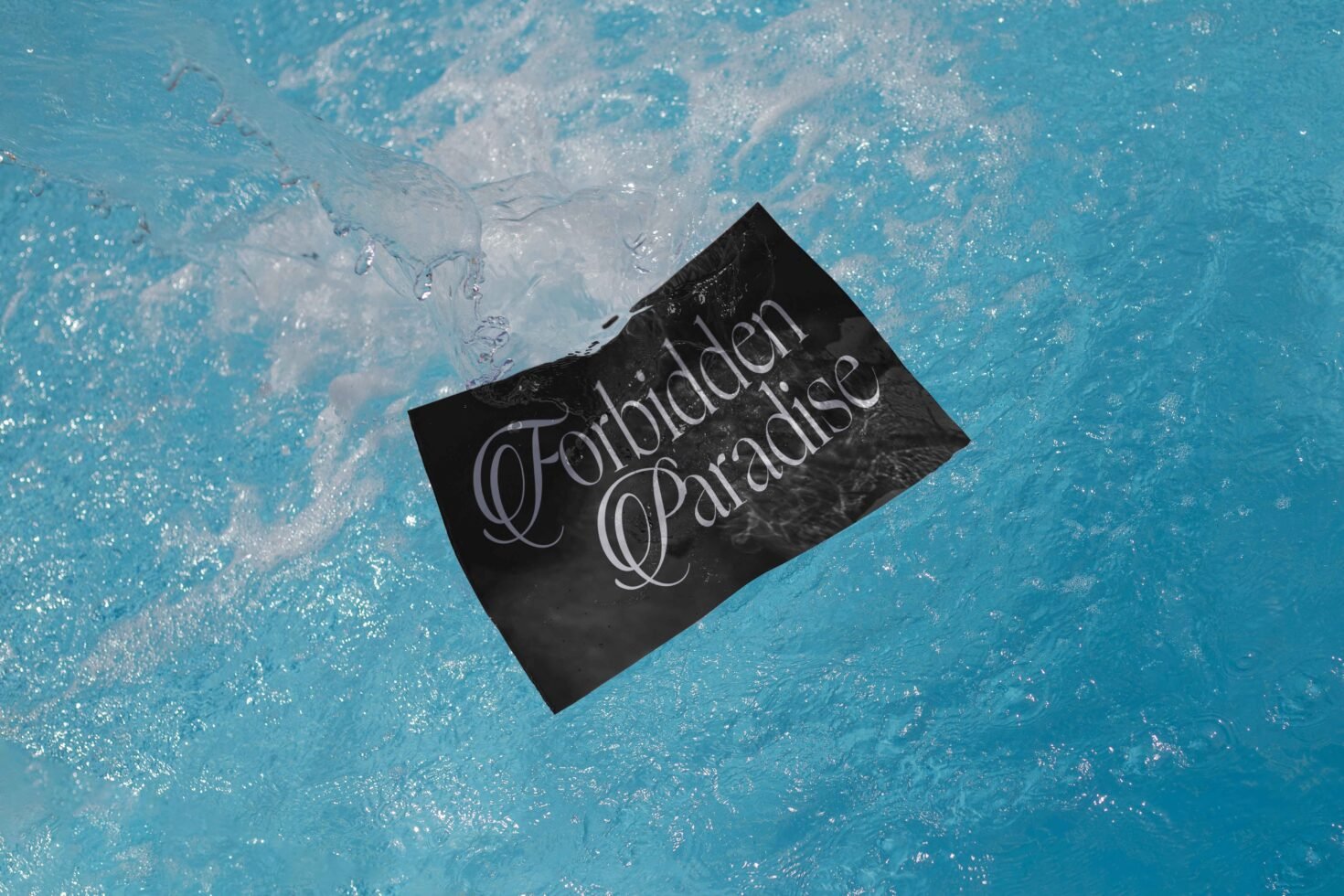 Elegant typography design on a black card submerged in vibrant blue water. Perfect for graphic designers looking for unique font inspiration and aquatic themes.