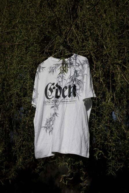 White oversized tee hanging on willow branches with leaf shadow overlay