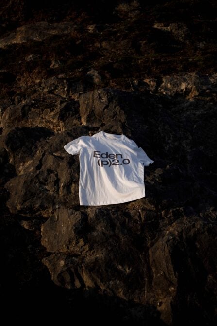 White t-shirt with text Eden p 2.0 displayed on dark rocky background perfect for apparel mockup designers template fashion branding casual wear.