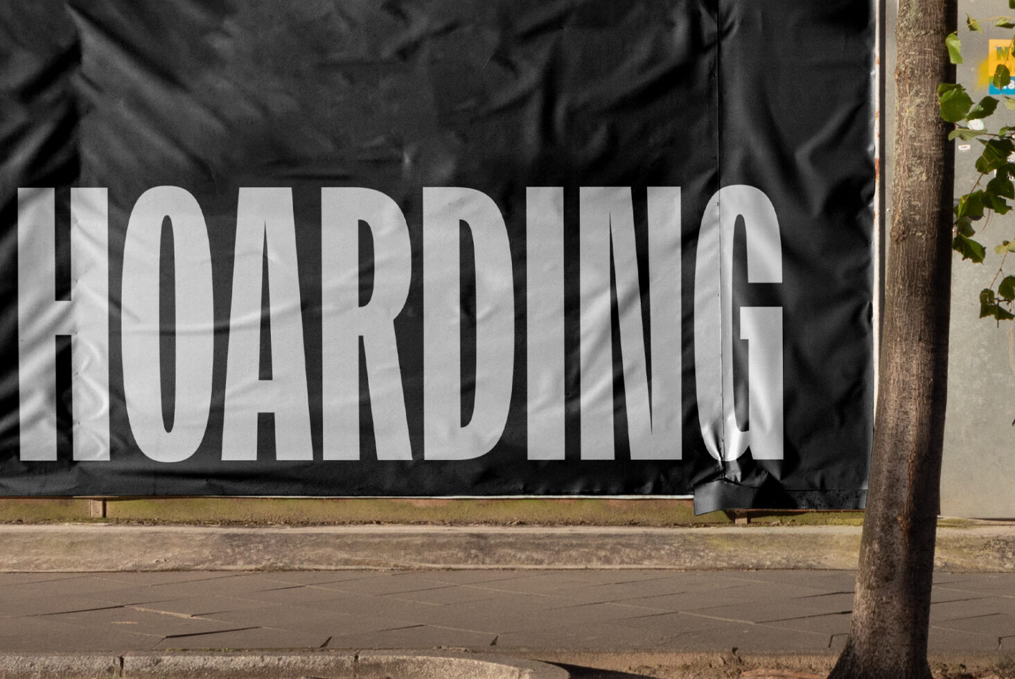 Large-scale black hoarding mockup with chunky white typography on street level