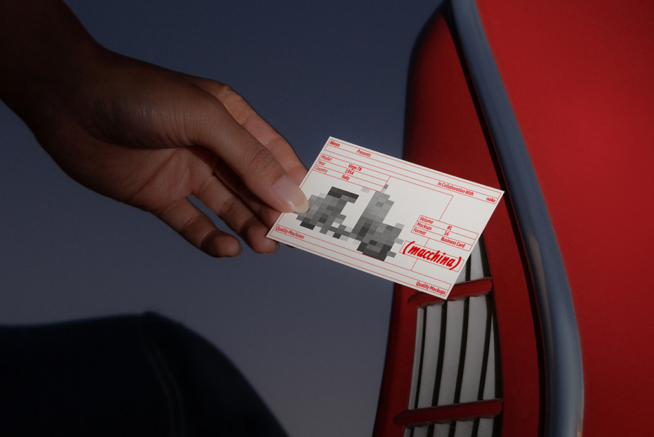 Business card with pixelated vintage car design held next to red car door