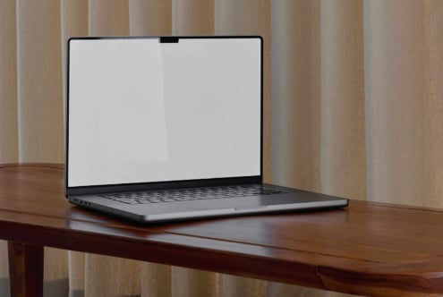 Laptop mockup on wooden table with blank screen for design presentations; ideal for showcasing digital assets for designers; modern minimalist setting