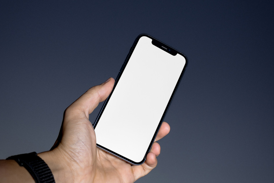 Hand holding black notch phone with blank white screen against dark blue backdrop