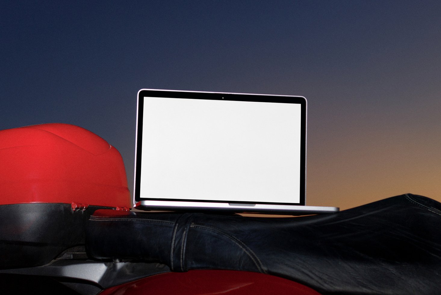 Laptop mockup on motorcycle seat with blank screen at sunset background ideal for showcasing website or app design templates in graphics projects.