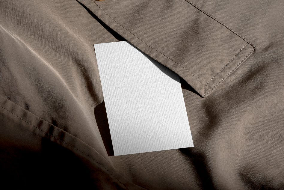 Blank white card on textured beige fabric with dramatic shadow cast by window light