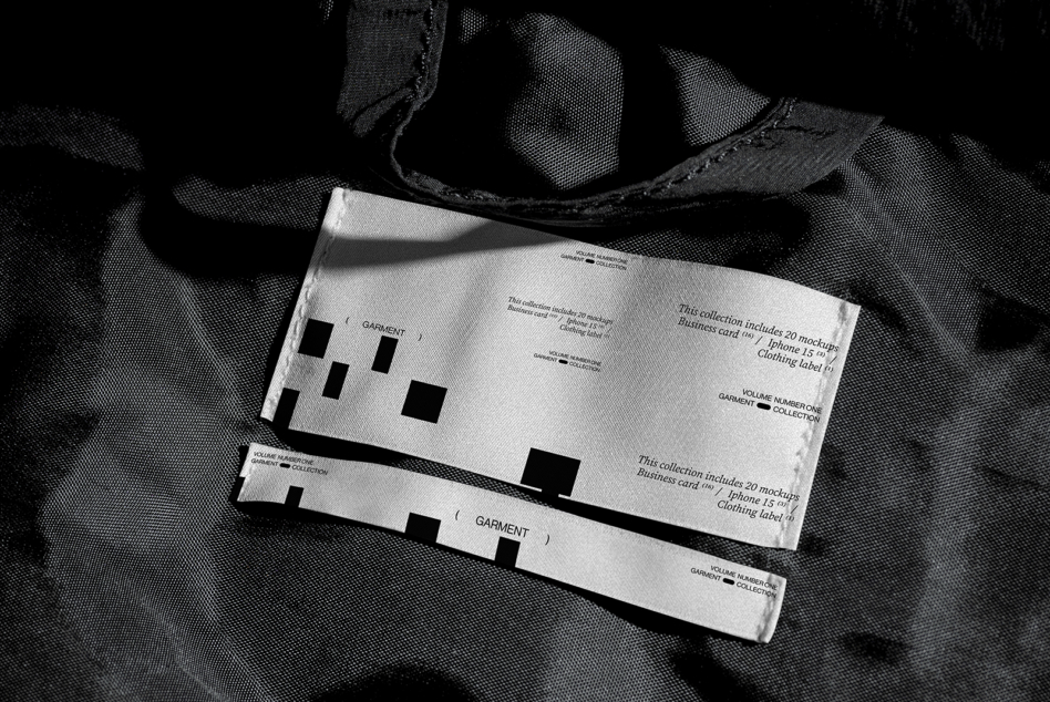 White clothing label with text mockup on black plaid fabric surface