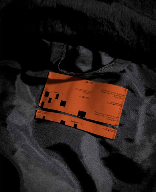 Orange clothing label tags stacked on plaid fabric with black stitching