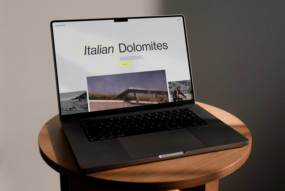 Laptop with Italian Dolomites website displayed on screen resting on a wooden table mockup technology design inspiration digital assets workspace photography.