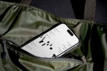 iPhone in olive cargo bag showing layout wireframes on screen