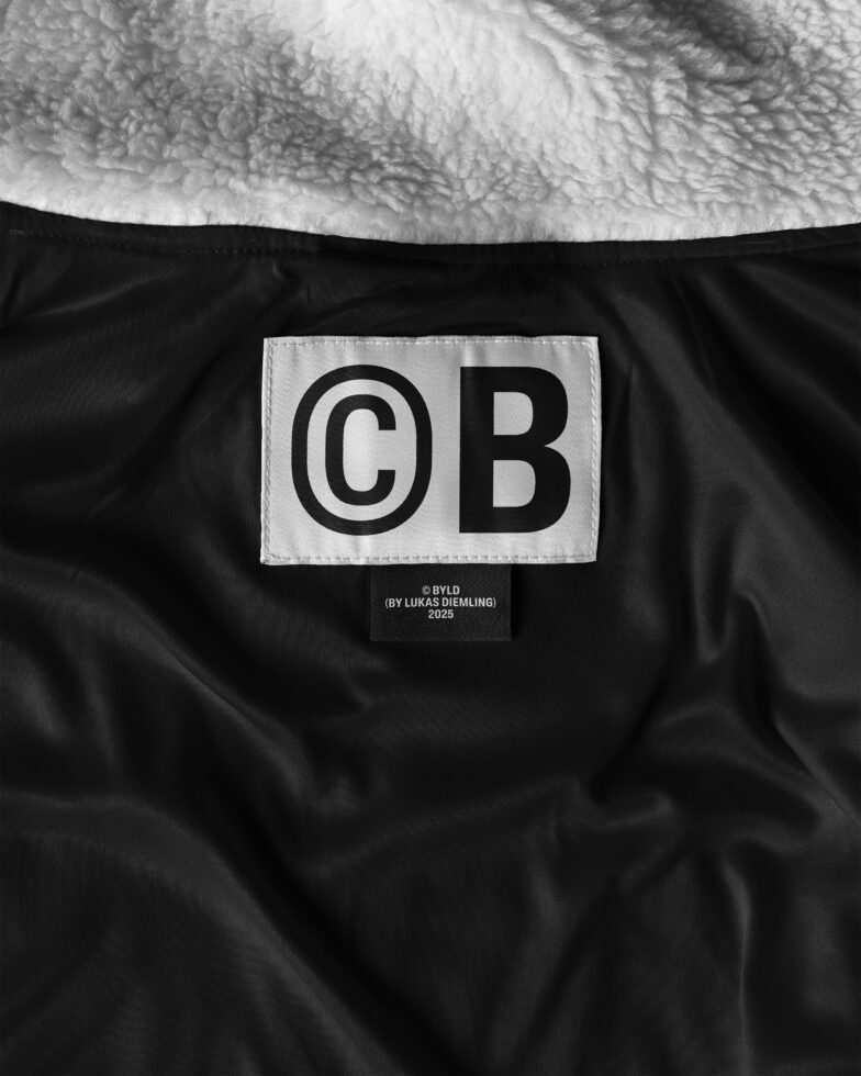 Jacket label close-up on a sherpa-lined black fabric with bold typography. Ideal for apparel templates and branding mockups. High-quality fashion graphic.