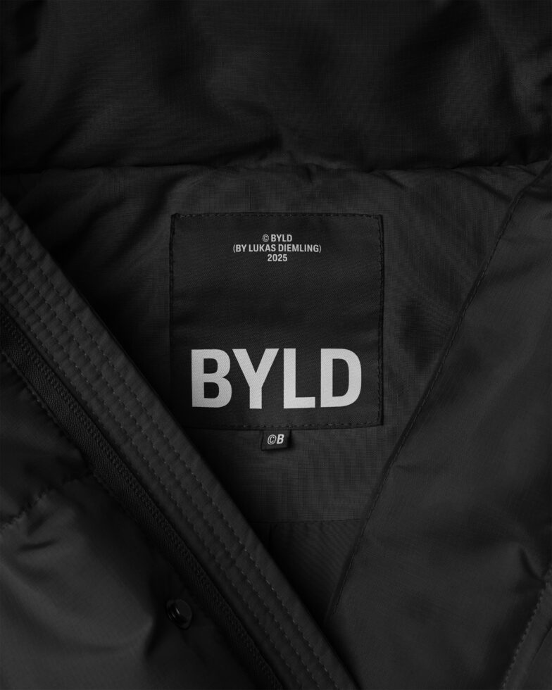 Close-up of a black jacket with a label reading BYLD 2023. Ideal for designers focused on texture, fashion mockups, or branding graphics.