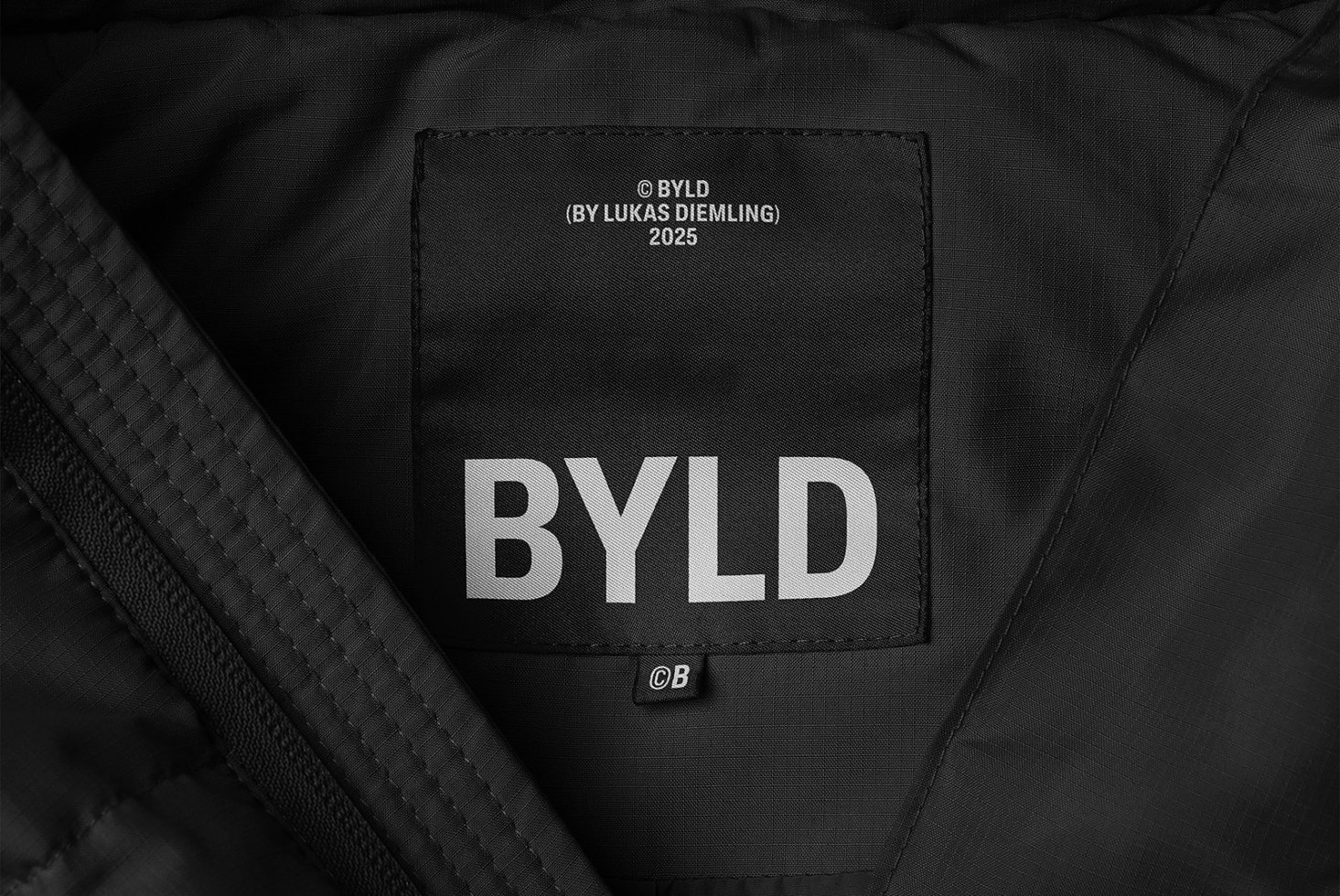 Close-up of a black textile label inside a garment displaying BYLD brand text. Ideal for fashion mockups and graphic design projects.