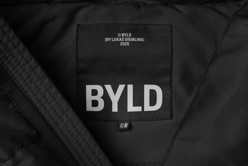 Close-up of a black textile label inside a garment displaying BYLD brand text. Ideal for fashion mockups and graphic design projects.