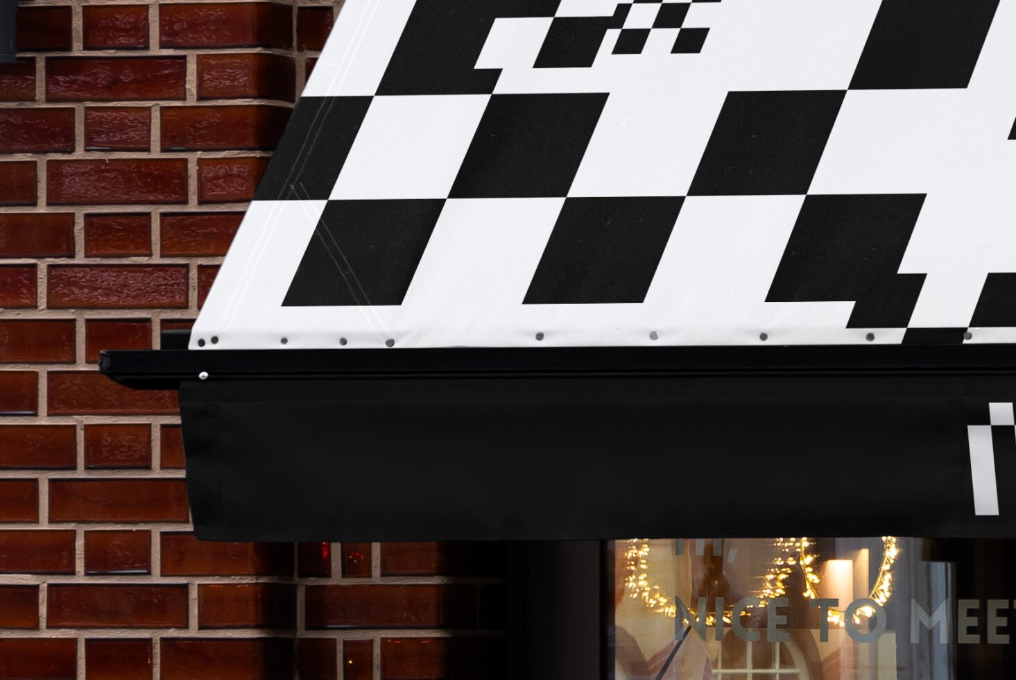 Shop awning with bold black and white geometric design, brick wall background. Ideal for branding mockups and signage templates for designers.
