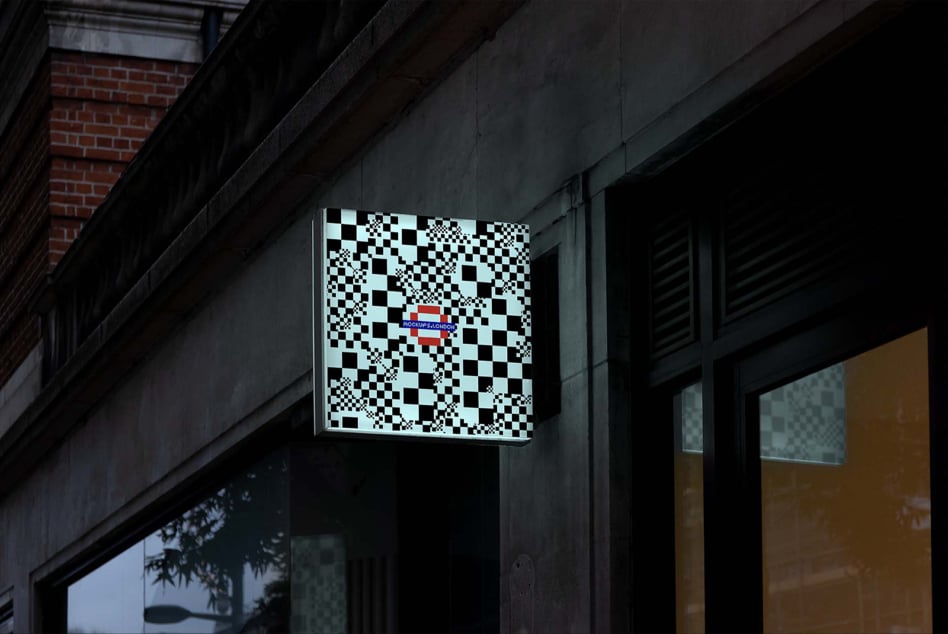 Illuminated signage cube on dark building facade showing checkerboard pattern