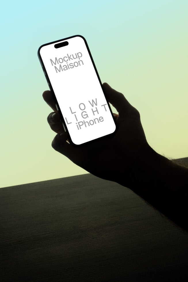 iPhone mockup in low-light setting, hand holding phone displaying text Mockup Maison, suitable for designers, digital assets, graphic templates, 3D.