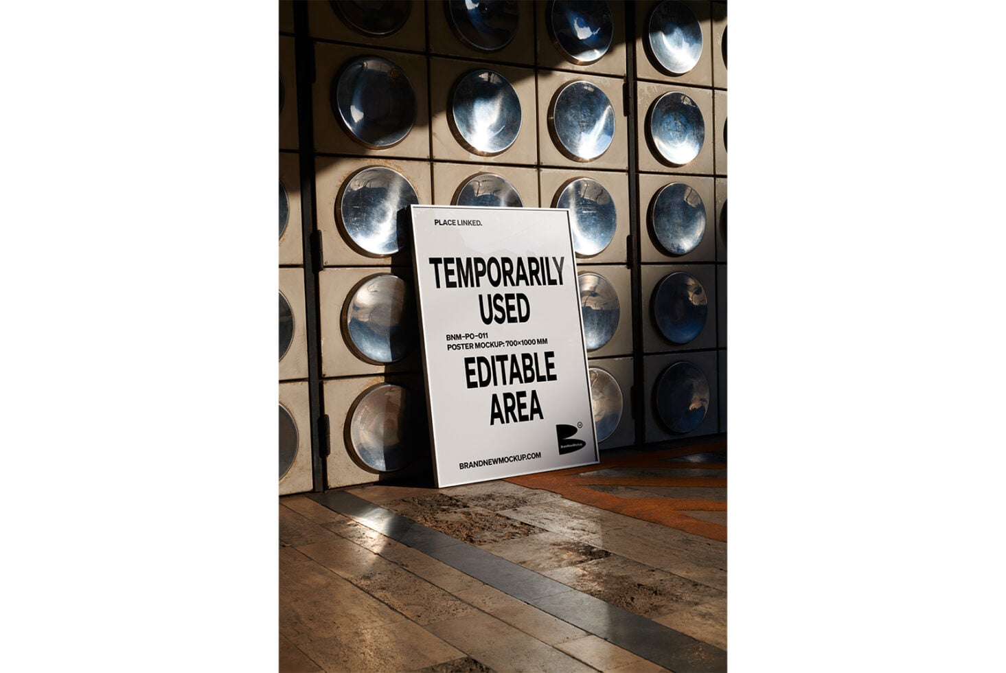 White poster propped on wooden floor with metal plate wall backdrop
