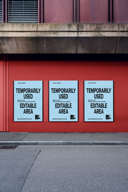 Three light blue posters hung on vibrant red wall under industrial overhang