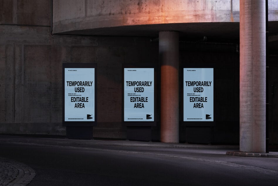 Three light blue posters mounted on dark storefront window at dusk with rust brick visible